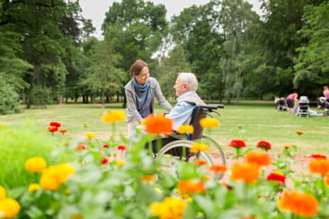 Caregiver and senior man on a wheelchair, walking in park