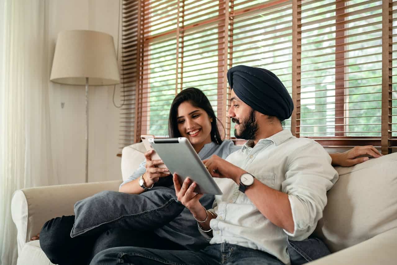 Couple sitting on couch looking at papers.